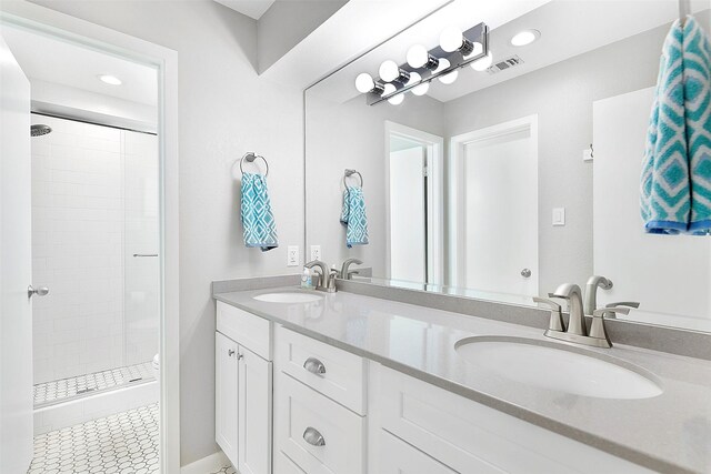 bathroom featuring tile patterned floors, a tile shower, and vanity