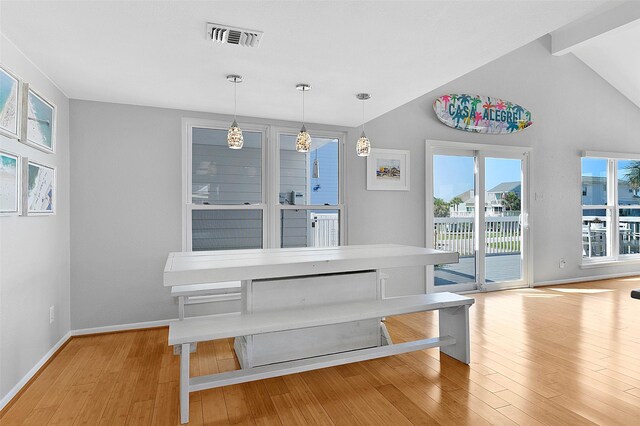 dining area with light wood-type flooring and lofted ceiling with beams