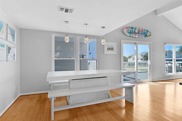 dining room featuring vaulted ceiling, light wood finished floors, visible vents, and baseboards