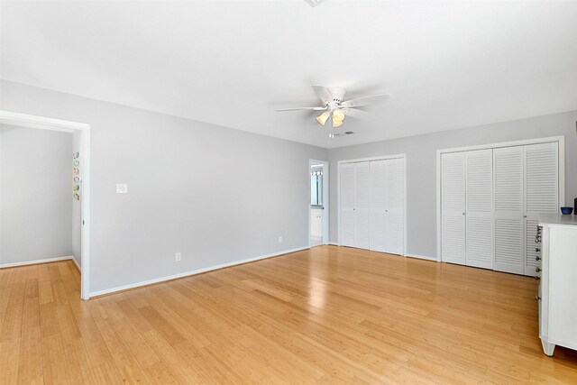 unfurnished bedroom with ceiling fan, multiple closets, and light hardwood / wood-style floors