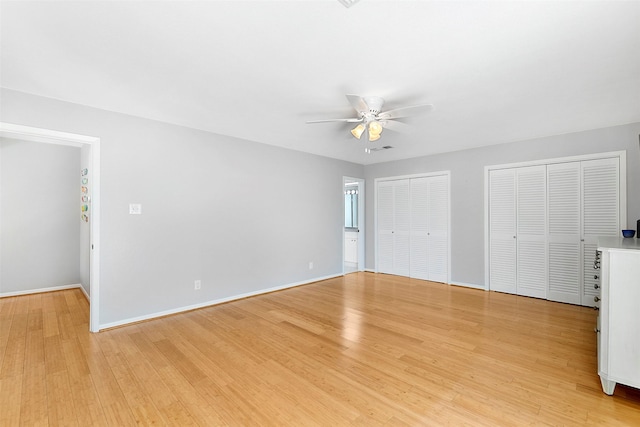 unfurnished bedroom with visible vents, baseboards, a ceiling fan, light wood-type flooring, and multiple closets