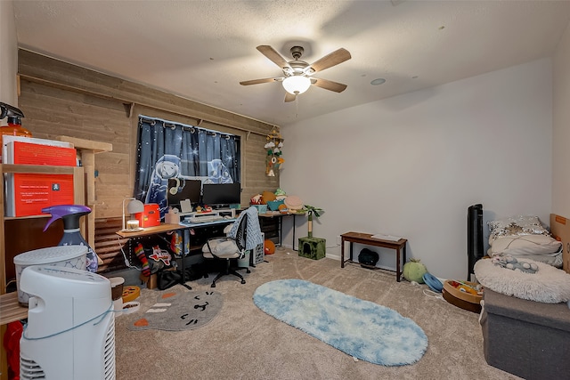 carpeted home office with wooden walls and ceiling fan