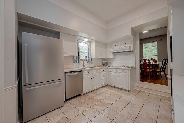 kitchen with stainless steel appliances, light hardwood / wood-style floors, a healthy amount of sunlight, and tasteful backsplash