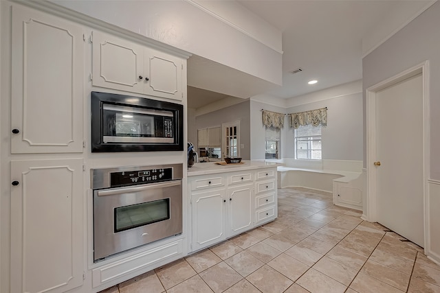 kitchen with light tile patterned flooring, stainless steel appliances, and white cabinets