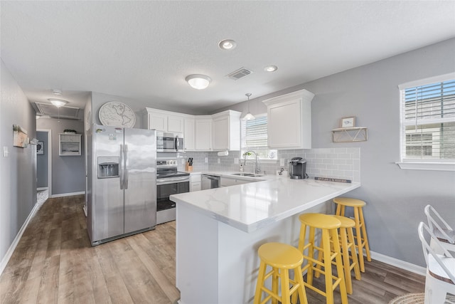 kitchen with stainless steel appliances, sink, decorative backsplash, a breakfast bar, and light hardwood / wood-style floors