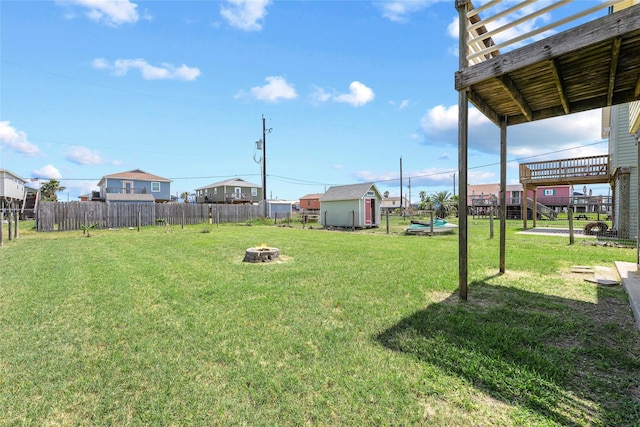 view of yard featuring a fire pit, a shed, fence, and an outdoor structure