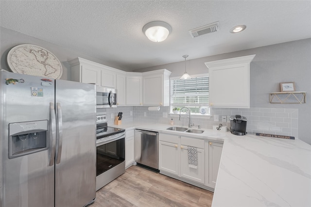 kitchen featuring light hardwood / wood-style flooring, backsplash, appliances with stainless steel finishes, sink, and white cabinetry