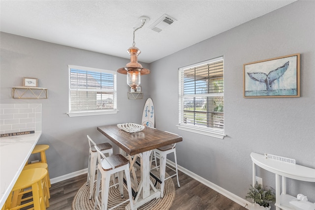 dining space featuring a textured ceiling and dark hardwood / wood-style flooring