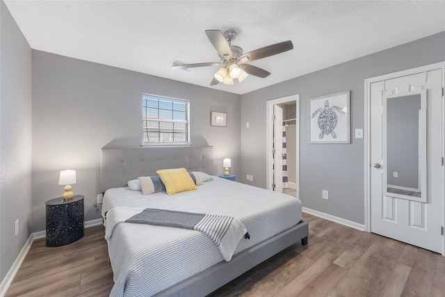 bedroom featuring ceiling fan, a spacious closet, baseboards, and wood finished floors