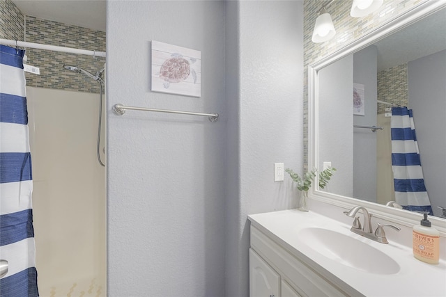 bathroom with a shower with curtain, a textured wall, and vanity