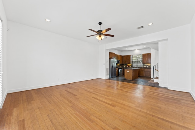 unfurnished living room featuring ceiling fan and hardwood / wood-style floors