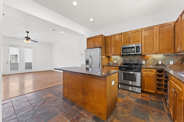 kitchen featuring ceiling fan, tasteful backsplash, stainless steel appliances, dark hardwood / wood-style floors, and a center island