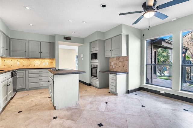 kitchen featuring gray cabinetry, backsplash, ceiling fan, a kitchen island, and stainless steel appliances