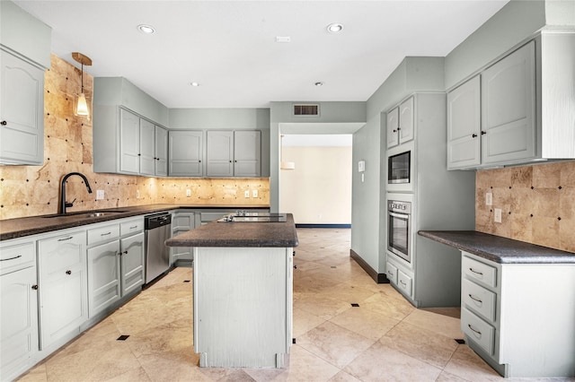 kitchen with gray cabinetry, sink, decorative backsplash, appliances with stainless steel finishes, and a kitchen island