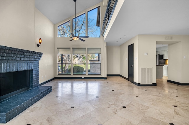 unfurnished living room featuring ceiling fan, a high ceiling, and a brick fireplace