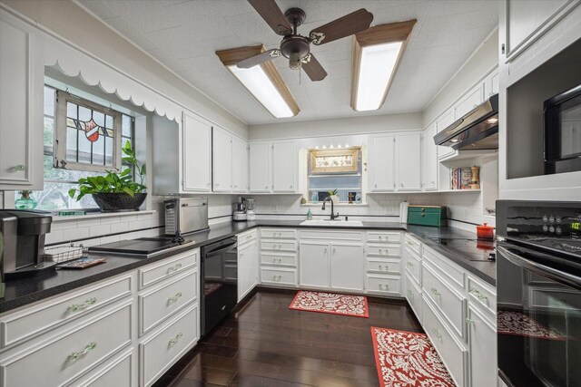 kitchen with dark hardwood / wood-style floors, tasteful backsplash, ventilation hood, sink, and black appliances