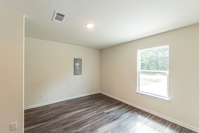 empty room featuring dark hardwood / wood-style flooring, a textured ceiling, and electric panel