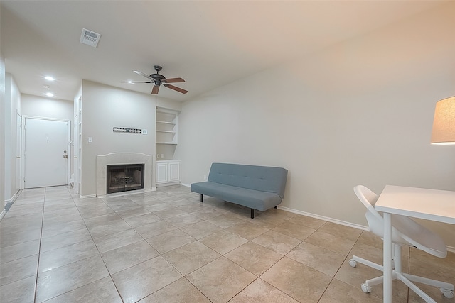 tiled living room featuring ceiling fan and built in shelves