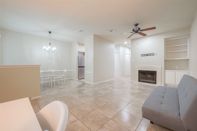 tiled living room featuring built in features and ceiling fan with notable chandelier