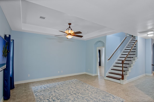 unfurnished living room with a raised ceiling and ceiling fan