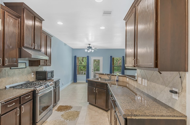 kitchen with tasteful backsplash, ceiling fan, appliances with stainless steel finishes, dark stone counters, and sink