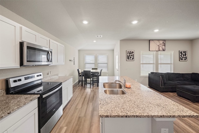 kitchen featuring sink, light hardwood / wood-style flooring, light stone counters, a kitchen island with sink, and stainless steel appliances