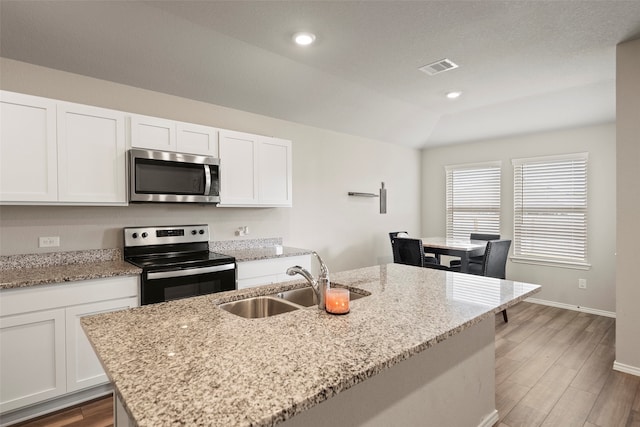 kitchen featuring light wood-type flooring, light stone counters, sink, lofted ceiling, and stainless steel appliances