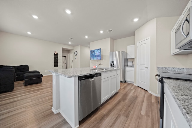 kitchen with white cabinets, light hardwood / wood-style floors, light stone countertops, and stainless steel appliances