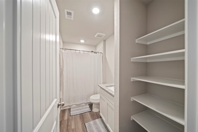 bathroom featuring hardwood / wood-style floors, toilet, vanity, and curtained shower