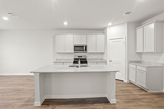 kitchen with white cabinets, stainless steel appliances, and a kitchen island with sink