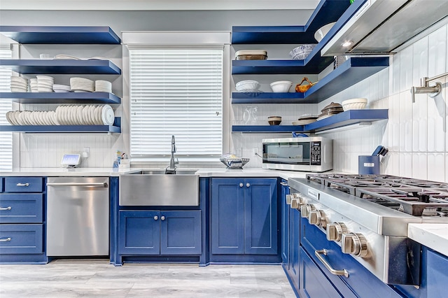 kitchen with light hardwood / wood-style flooring, backsplash, stainless steel appliances, and blue cabinetry