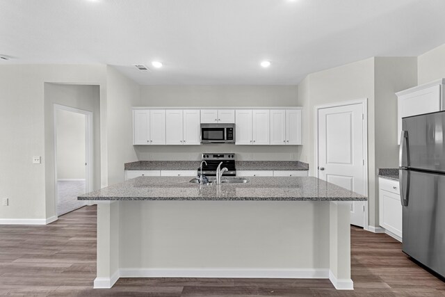 kitchen with white cabinetry, a kitchen island with sink, stainless steel appliances, and hardwood / wood-style floors