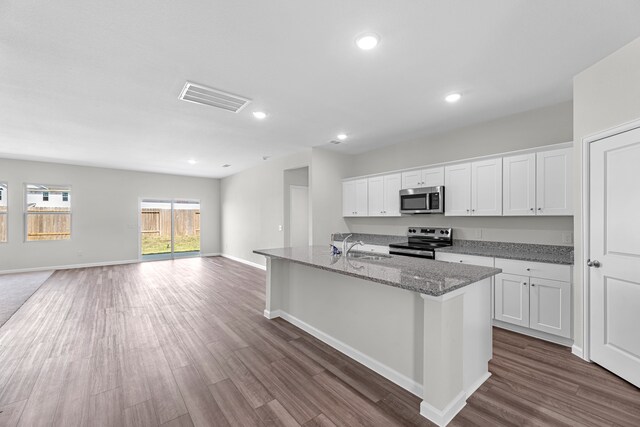 kitchen with appliances with stainless steel finishes, an island with sink, white cabinetry, and dark hardwood / wood-style flooring