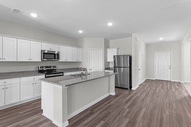 kitchen with light stone countertops, an island with sink, dark hardwood / wood-style flooring, white cabinetry, and stainless steel appliances