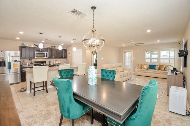 dining space with ceiling fan with notable chandelier and light tile patterned floors