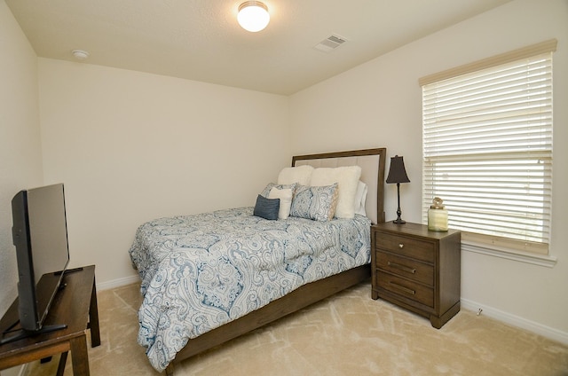 bedroom with visible vents, light carpet, and baseboards