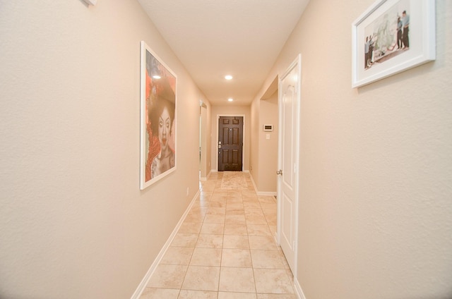 hall featuring light tile patterned flooring and baseboards