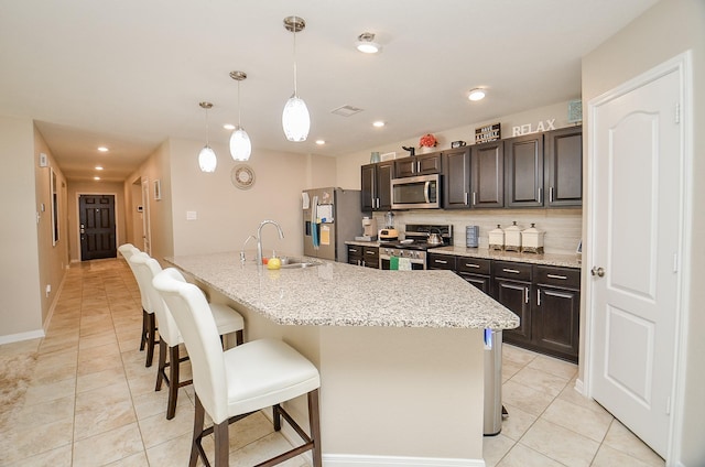 kitchen with backsplash, a breakfast bar area, an island with sink, appliances with stainless steel finishes, and a sink