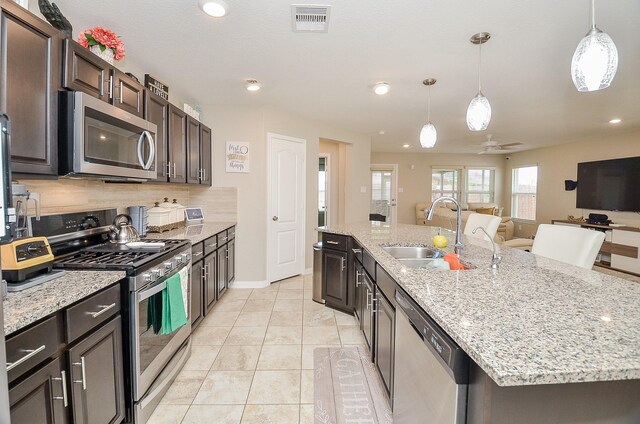 kitchen with appliances with stainless steel finishes, pendant lighting, ceiling fan, a kitchen island with sink, and sink