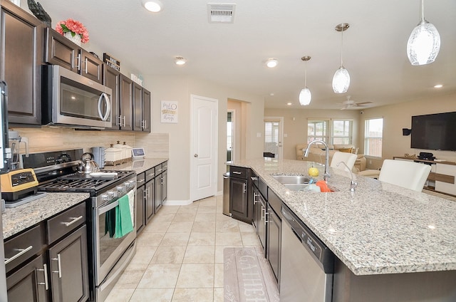 kitchen featuring visible vents, backsplash, a large island, stainless steel appliances, and a sink