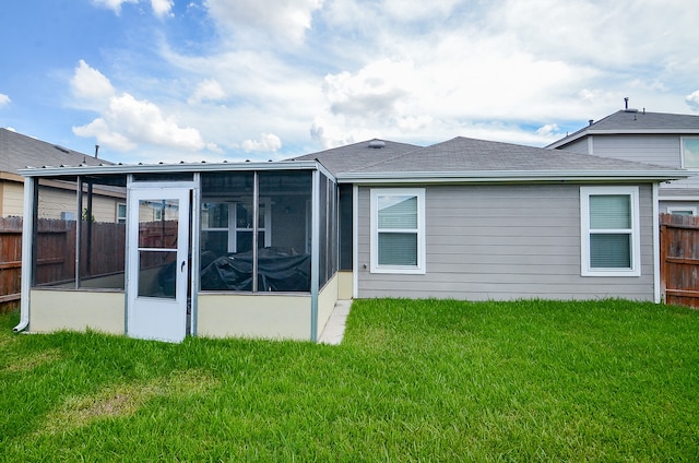 rear view of house with a sunroom and a yard