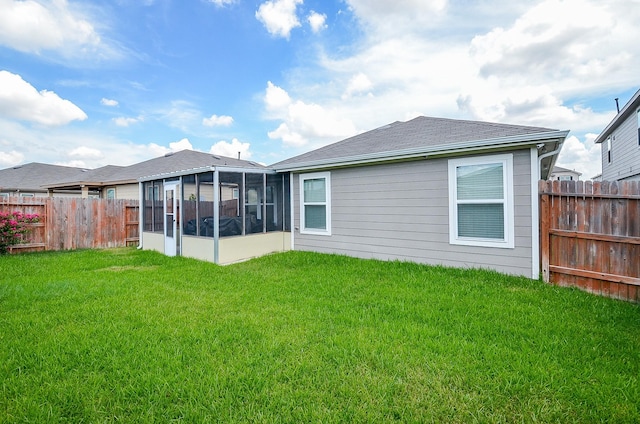 rear view of property featuring a yard, fence, and a sunroom