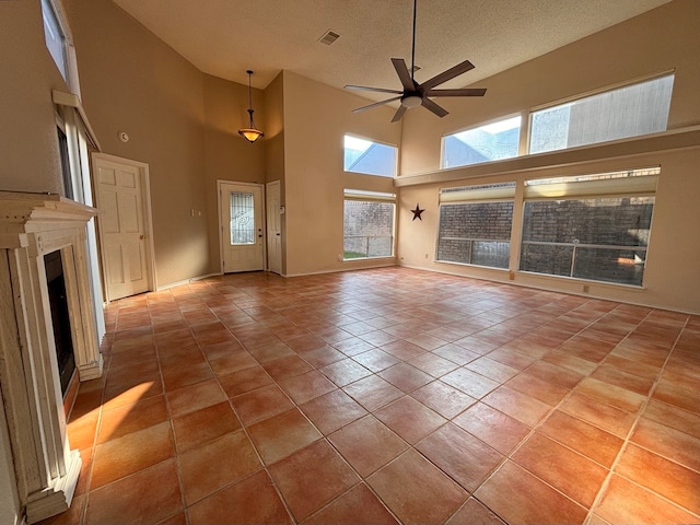 unfurnished living room with ceiling fan, a textured ceiling, light tile patterned floors, and high vaulted ceiling