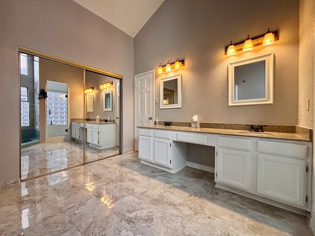 bathroom featuring high vaulted ceiling and vanity