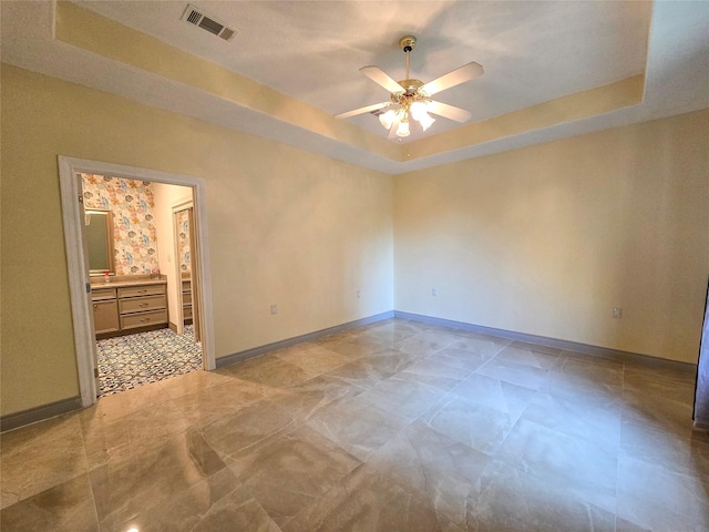 unfurnished room with ceiling fan and a tray ceiling