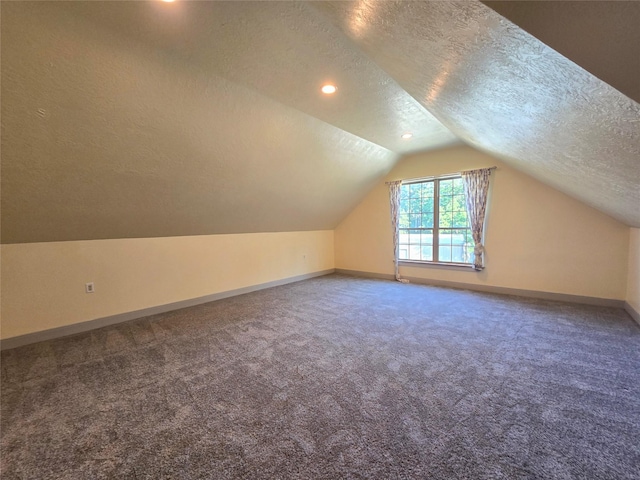 additional living space featuring lofted ceiling, carpet floors, and a textured ceiling