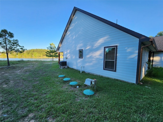 view of side of home featuring central AC, a lawn, and a water view