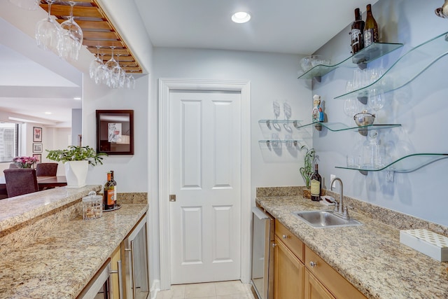 bar featuring beverage cooler, light stone counters, light tile patterned floors, and sink