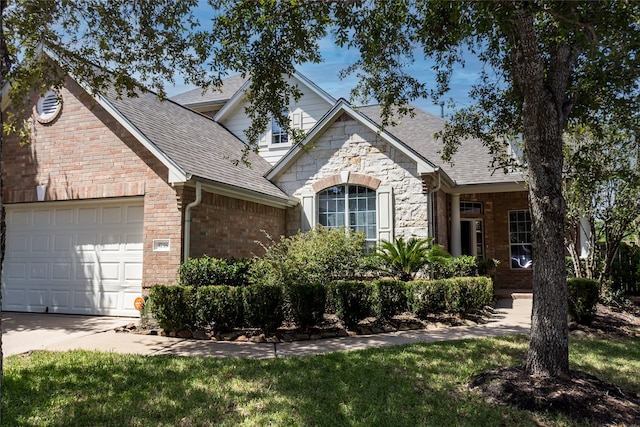 traditional-style house featuring an attached garage, driveway, brick siding, and a shingled roof