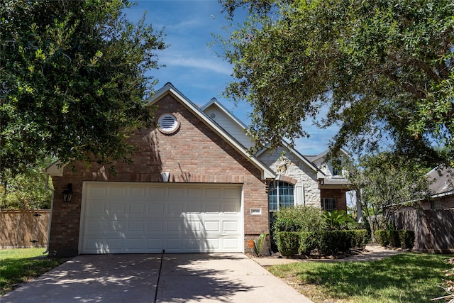 traditional-style home featuring driveway, an attached garage, fence, and brick siding